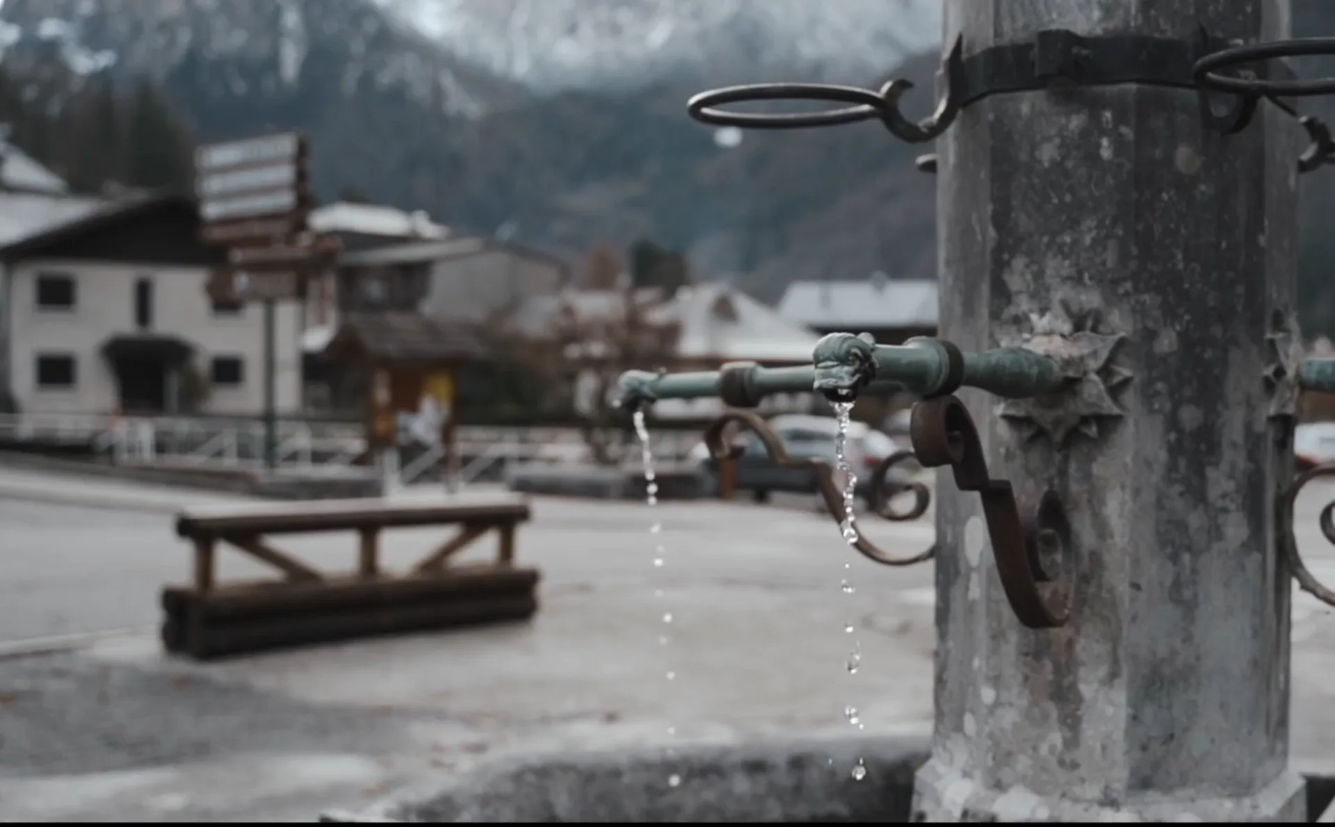 Gros plan sur la fontaine d'une place avec des montagnes en fond